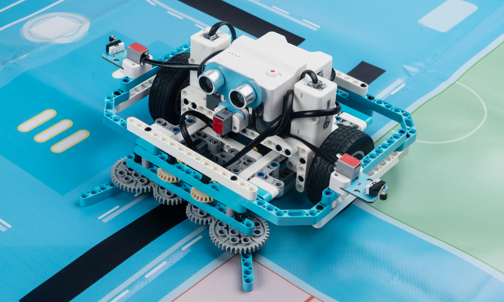 Steam Robotics Kit 110 robot car with ultrasonic sensor and gear system built from programmable blocks on a blue STEM learning map