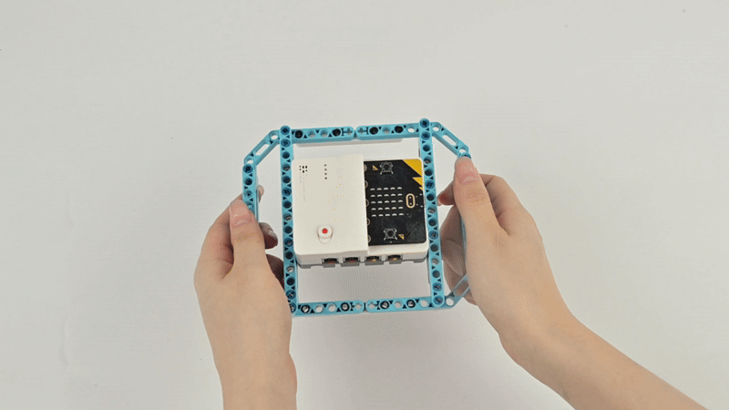 Hands assembling the Steam Robotics Kit 110 controller with micro:bit into a blue structural frame