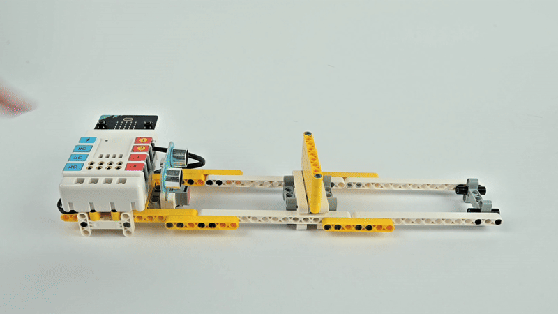 STEM robotics kit with programmable motor moving a yellow sliding mechanism for engineering experiment