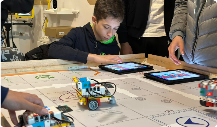 Children programming Nezha coding robotic kit robot cars with tablets in a classroom robotics activity