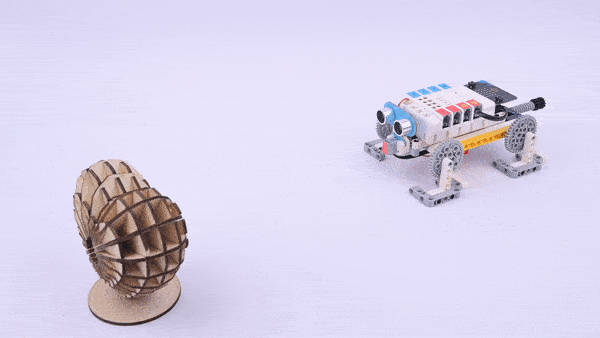 Nezha coding robotic kit robot car built with LEGO compatible parts moving toward a wooden obstacle